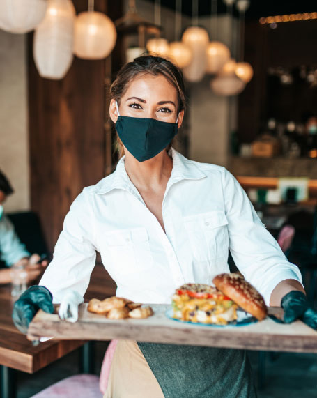 Server wearing a mask serving food at a restaurant